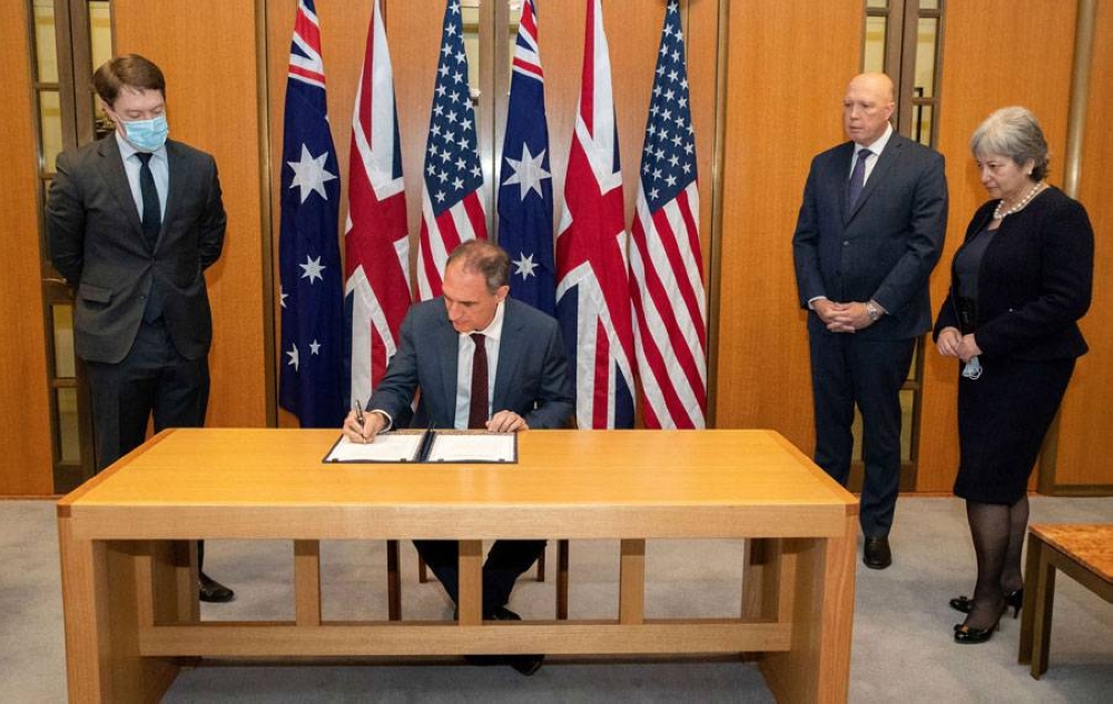 This handout photo taken and released on November 22, 2021 by the Australian Defence Force shows US Chargé d’Affaires Michael Goldman (2nd L) signing the Exchange of Naval Nuclear Propulsion Information Agreement as Australia's Minister for Defence Peter Dutton (2nd R) and British High Commissioner Victoria Treadell (R) look on during a ceremony at Parliament House in Canberra. AUSTRALIAN DEFENCE FORCE / AFP PHOTO