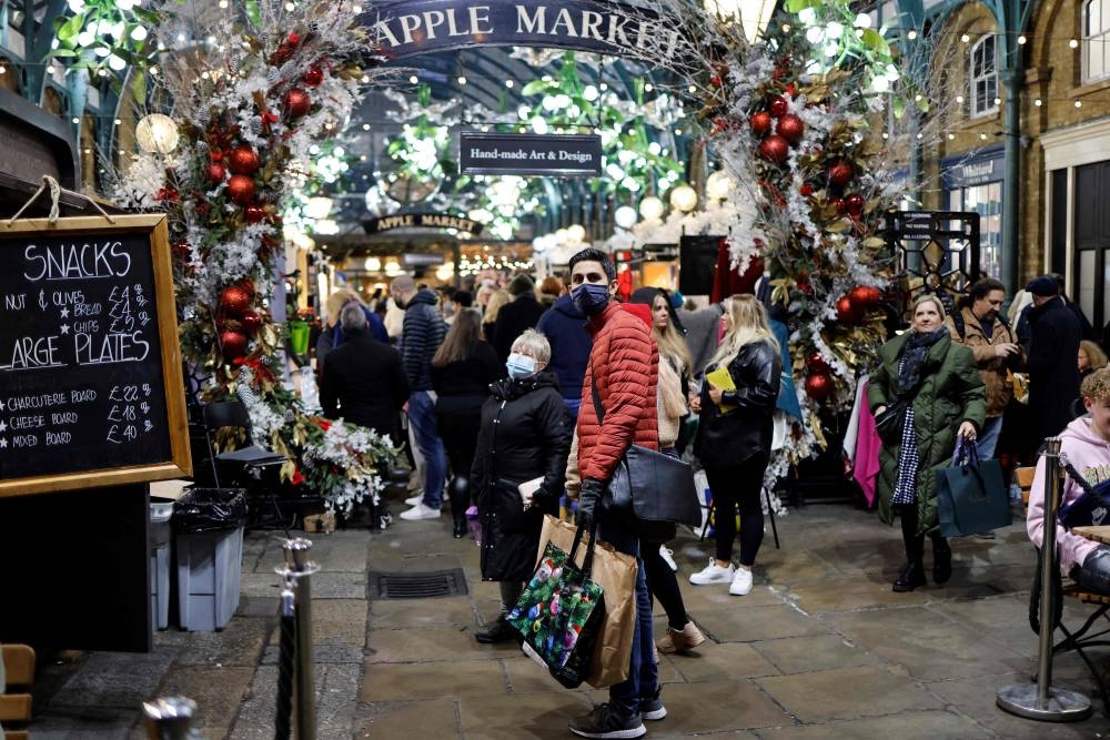 Shoppers, some wearing face coverings to combat the spread of Covid-19, walk past stalls and shops in the Apple Market in Covent Garden on the last Saturday for shopping before Christmas, in central London on December 18, 2021. AFP PHOTO