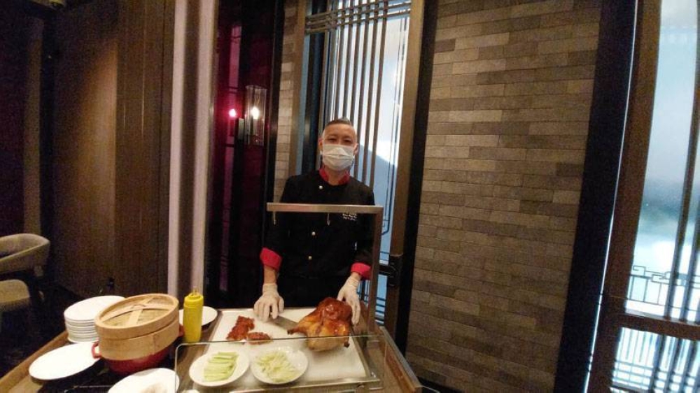 主厨 Raymond Young 根据 500 年历史的北京风味食谱烹制和准备北京烤鸭