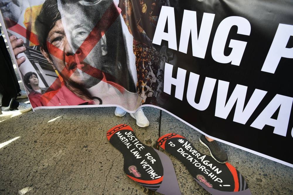Protesters hold a banner with a portrait of presidential aspirant Bongbong Marcos, son of the late dictator Ferdinand Marcos, during a demonstration to commemorate the 36th anniversary of the People Power Revolution in 1986 that ousted the dictator, in front of the People Power monument in Quezon City, suburban Manila on February 25, 2022. AFP PHOTO