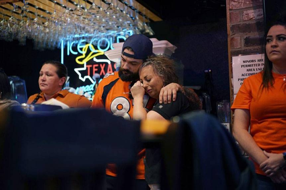 ROAD TRAGEDY Erik Herring, center left, and Andera Concotelli console each other during a memorial for Jackson Zinn at a Texas Roadhouse restaurant, Thursday, March 17, 2022, in Hobbs, New Mexico. Zinn, who worked at the restaurant, was killed with several other student golfers and the coach of University of the Southwest in a crash in Texas. PHOTO BY AP