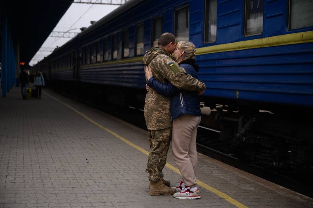 A Ukrainian serviceman hugs a woman as a train prepares to leave the main railway station in Zaporijia, southern Ukraine, on April 17, 2022. AFP PHOTO