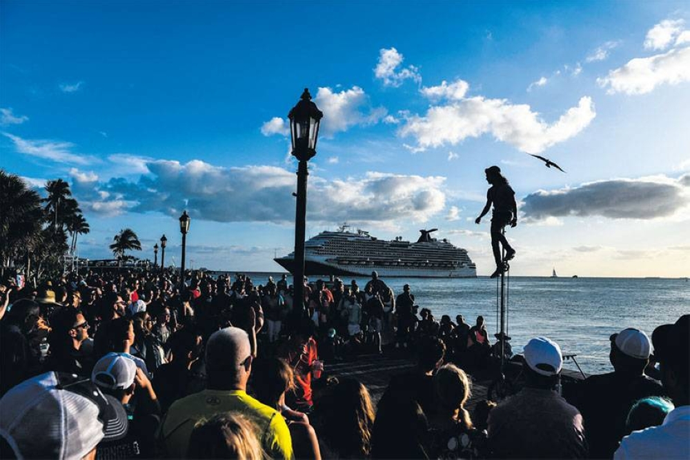 FINDING BALANCE People watch an artist
perform as the Carnival Dream cruise ship sails in Key West, Florida on
April 11, 2022. The island-city of Key West off the southern tip of Florida invites visitors to stroll slowly, enjoy turquoise waters and take in the sunset. But according to some residents, that idyllic peace is endangered  by lumbering, tourist-filled cruise ships. AFP PHOTO