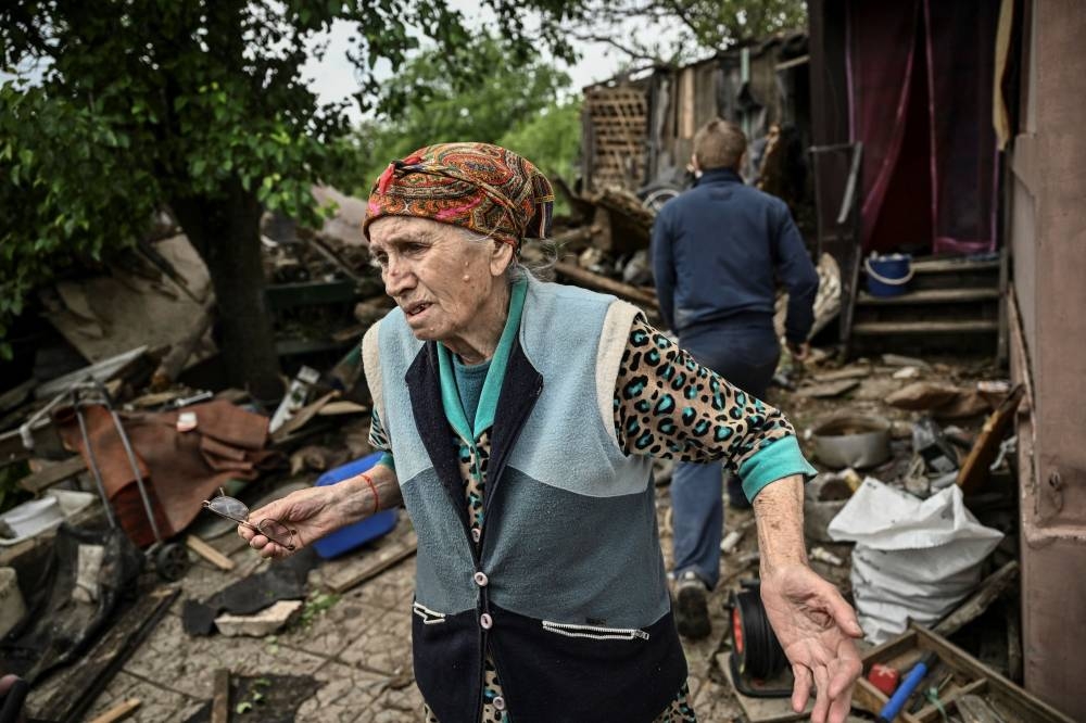 An eldery woman stands outside her heavily damaged house after it was hit by a missile in the city of Bakhmut in the eastern Ukranian region of Donbass on May 22, 2022, amid Russian invasion of Ukraine. AFP PHOTO