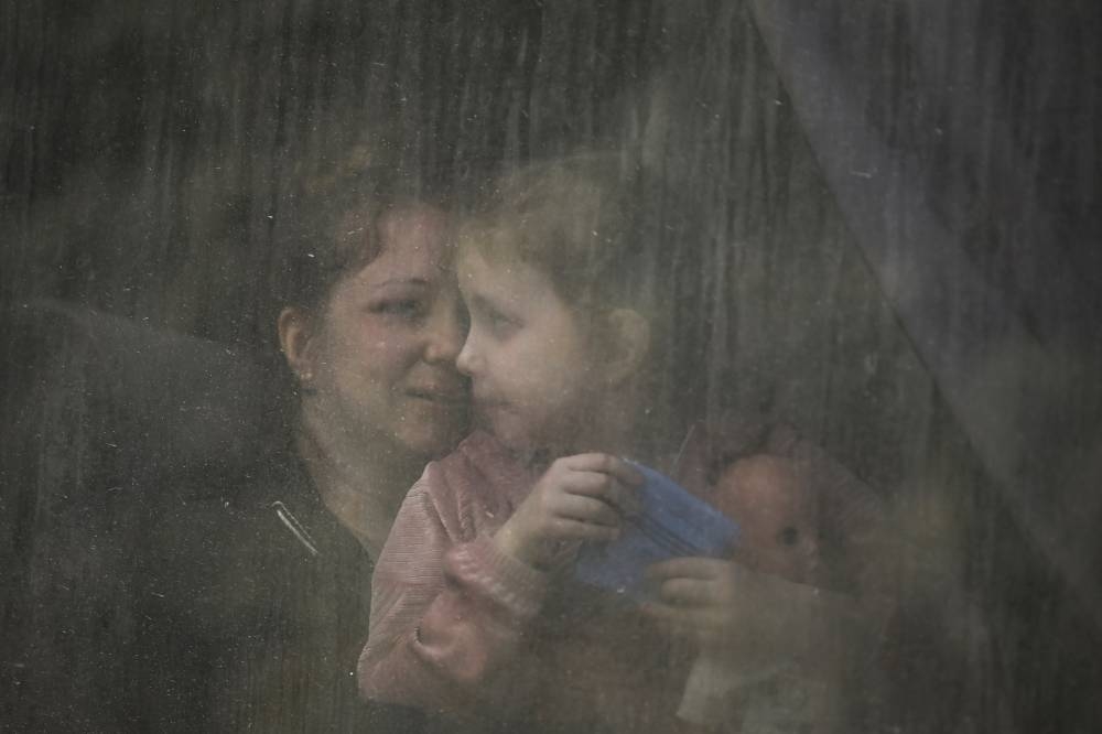 A mother with her daughter sit inside a bus as they evacuate the city of Bakhmut at the eastern Ukranian region of Donbas on May 22, 2022, amid Russian invasion of Ukraine. AFP PHOTO
