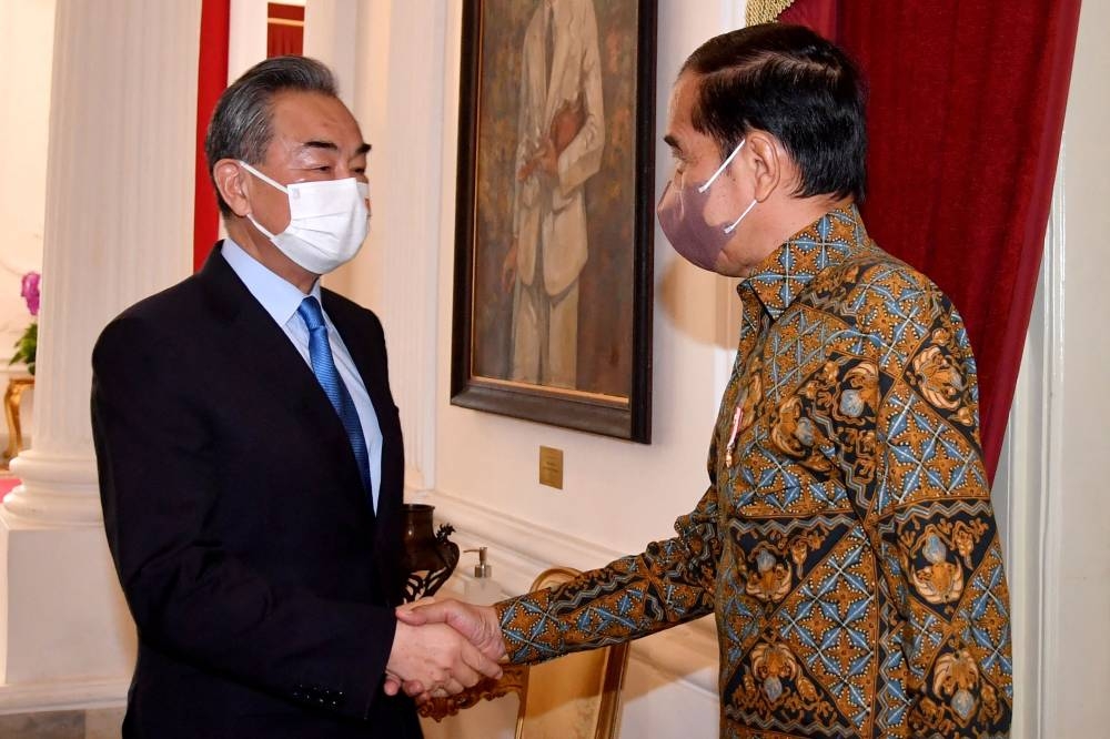 This handout taken and released by the Presidential Palace on July 11, 2022 shows Indonesian President Joko Widodo (right) shaking hands with China's Foreign Minister Wang Yi at the Merdeka Palace in Jakarta. AFP PHOTO / PRESIDENTIAL PALACE / RUSMAN 