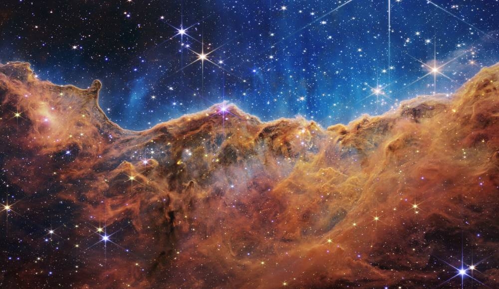 This image released by NASA on July 12, 2022, from the James Webb Space Telescope (JWST) shows a landscape of “mountains” and “valleys” speckled with glittering stars which is actually the edge of a nearby, young, star-forming region called NGC 3324 in the Carina Nebula. AFP PHOTO / NASA