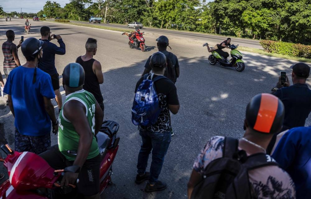People watch a drag race between two electric scooterists at a late afternoon gathering of electric motorbike owners to show off stunts and races in Havana, Cuba, Friday, July 15, 2022. AP PHOTO