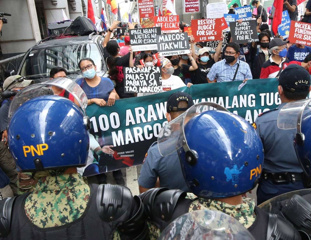 THROUGH THE BARRICADE Policemen block rallyists from marching to the Mendiola Peace Arch in Manila to mark the first 100 days of President Ferdinand Marcos Jr.’s administration on Saturday, Oct. 8, 2022. Marcos and running mate Sara Duterte won by a landslide in the May 2022 elections on a platform of unity. PHOTO BY RENE H. DILAN