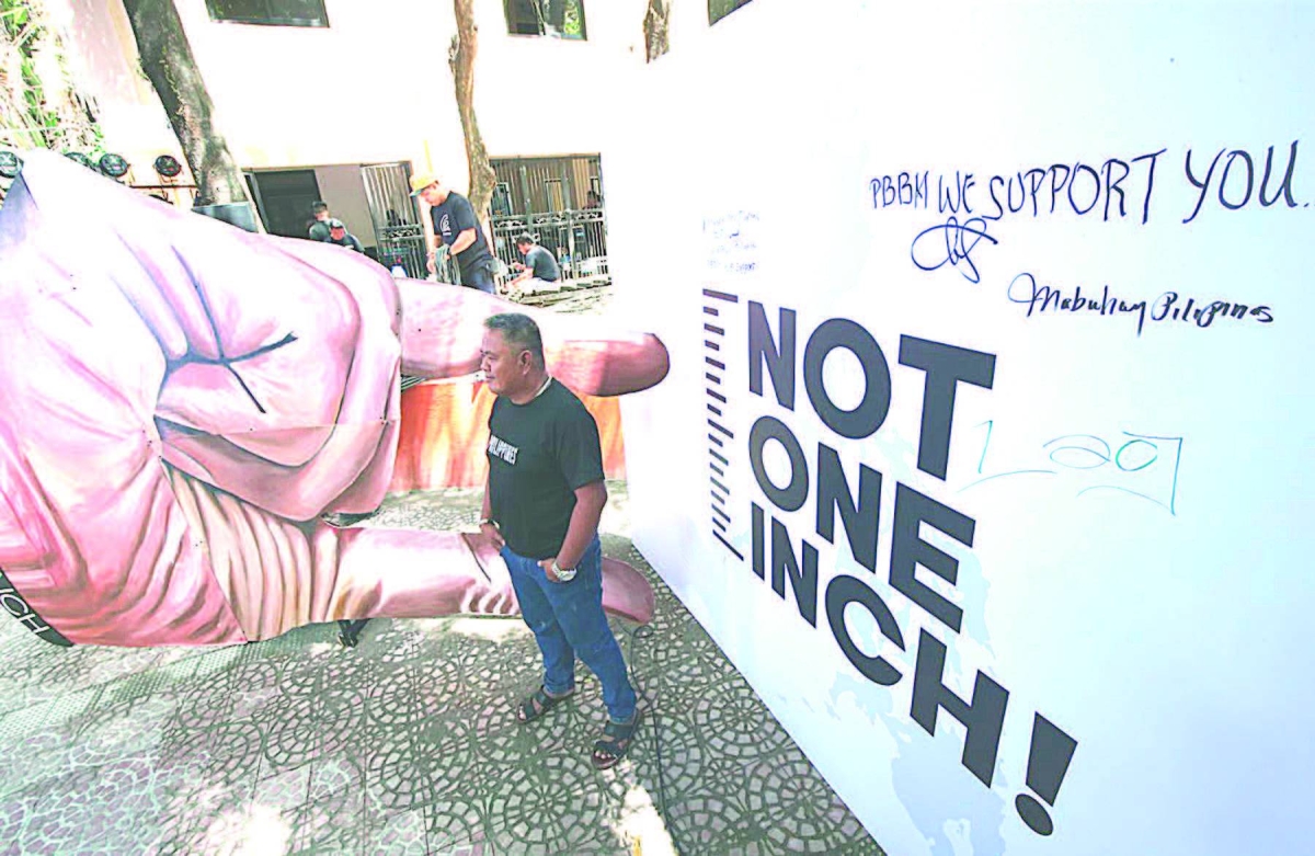 NO MORE, NO LESS A man on Saturday, March 25, 2023, stands in front of an image put up by the Alliance of West Philippine Sea Watchers that says ‘not one inch.’ The quote was part of President Ferdinand Marcos Jr.’s speech before the Philippine Military Academy where he assured Filipinos that the country would not cede a single Philippine-owned territory to Beijing in the South China Sea (SCS). The alliance aims to raise awareness on the issues about the West Philippine Sea, which lies within the SCS. PHOTO BY RENE H. DILAN