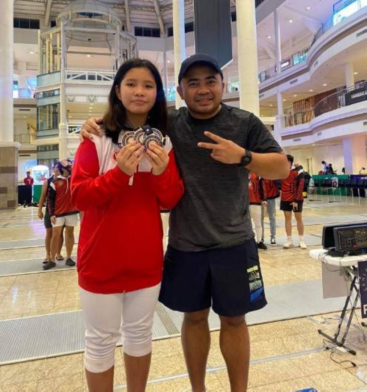 Sophia Catantan of University of the East/Canlas Fencing with coach Rolando “Amat” Canlas Jr. celebrate after winning her fourth gold medal in the 1st Burlington Inter-Club International Fencing Challenge at the Alabang Town Center in Muntinlupa City. CONTRIBUTED PHOTO