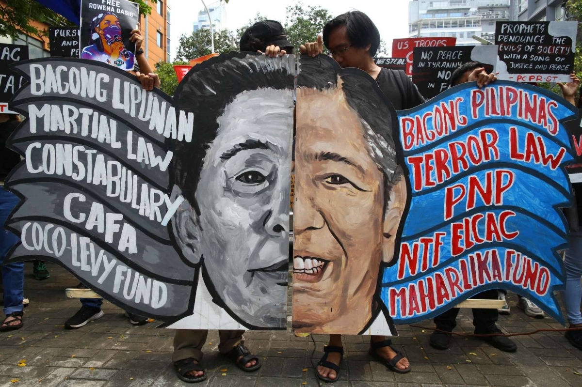 Members of Defend Southern Tagalog (DEFEND ST) group hold up a two-faced Marcos mural, depicting the like-father, like-son parallelisms of their Marcosian regime, during a demonstration rally in commemoration of the 51st anniversary of the Martial Law declaration, held along Roxas Boulevard across the United States Embassy in Manila, on 21 September 2023.  PHOTO by Mike Alquinto
