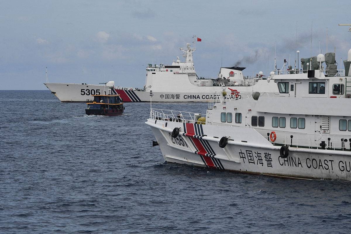 Chinese coast guard ships (L and R) corralling a Philippine civilian boat chartered by the Philippine navy to deliver supplies to Philippine navy ship BRP Sierra Madre in the disputed South China Sea, on August 22, 2023. The Philippines accused a Chinese coastguard vessel of colliding on October 22, 2023 with a Philippine resupply boat as it travelled to a tiny garrison in the disputed South China Sea. Ted ALJIBE / AFP