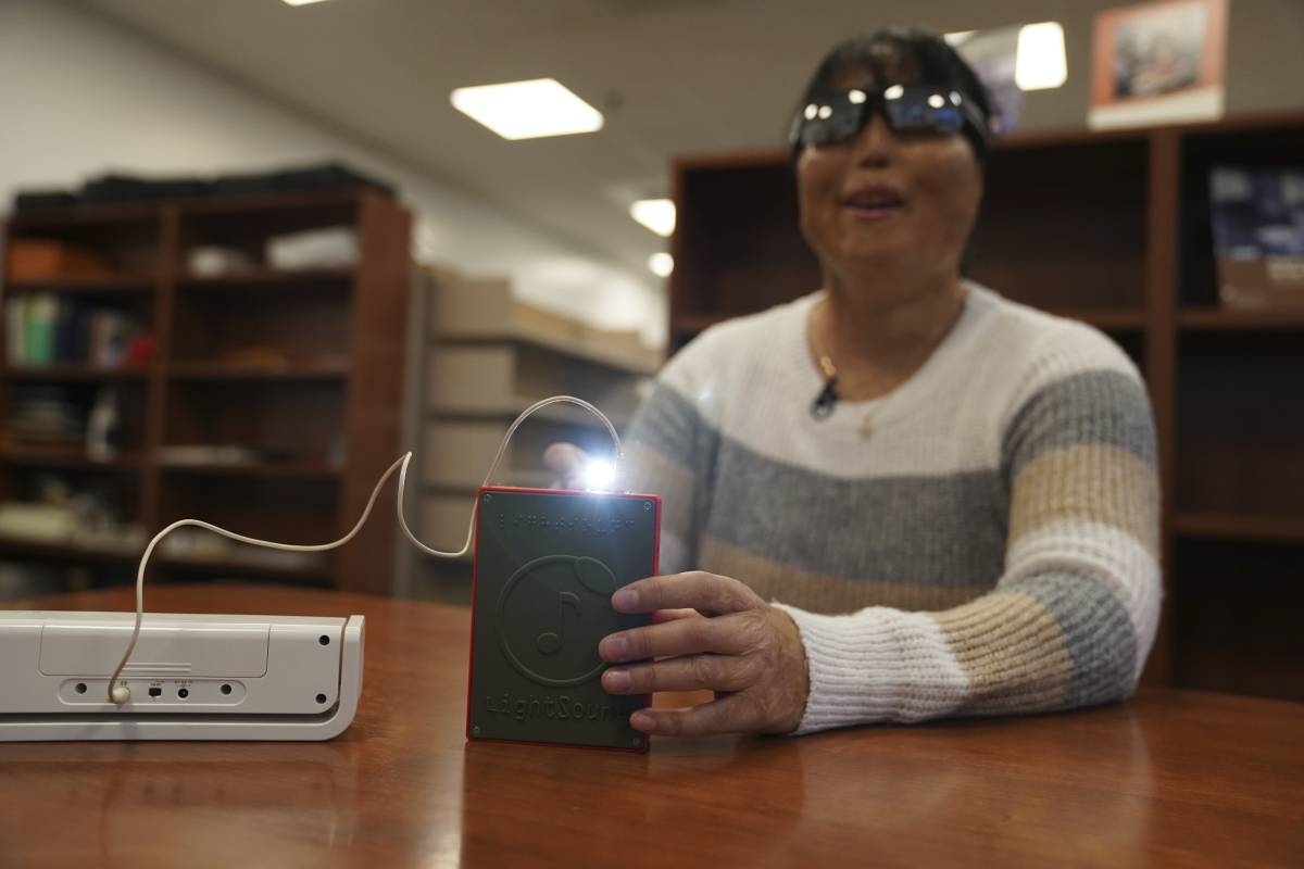 Minh Ha, assistive technology manager at the Perkins School for the Blind, tries a LightSound device for the first time at the school’s library in Watertown, Massachusetts, on March 2, 2024. As eclipse watchers look to the skies in April 2024, new technology will allow people who are blind or visually impaired to hear and feel the celestial event. AP PHOTO