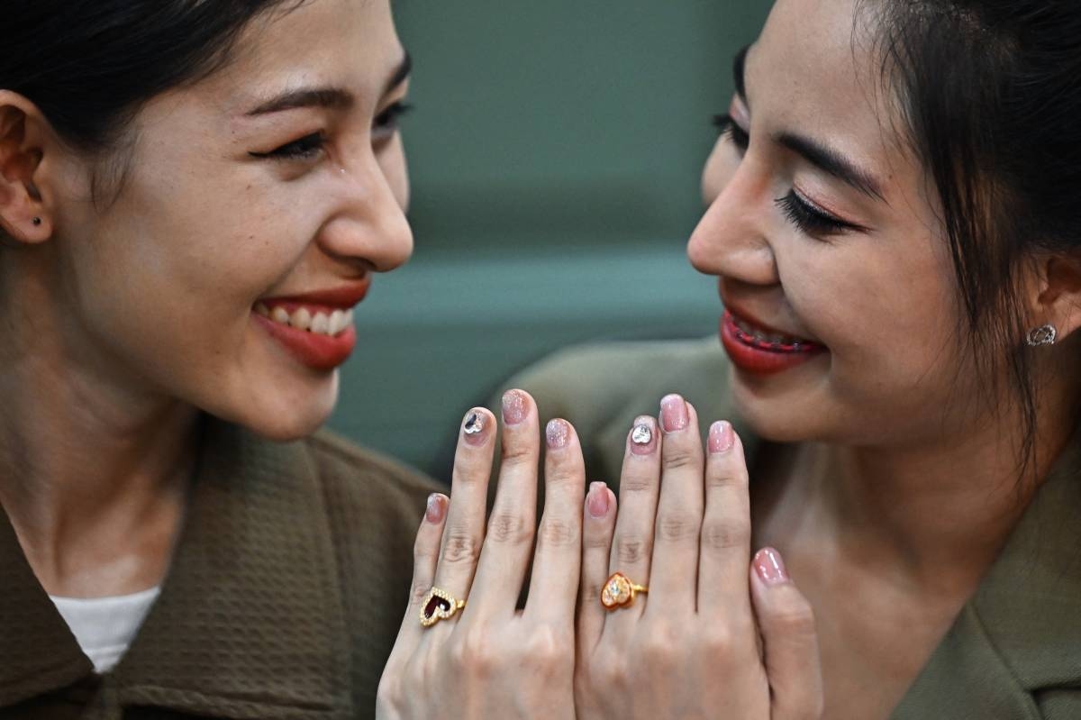 An LGBTQIA couple shows off their rings for photographers during a symbolic marriage registration event despite Thailand not recognising same-sex marriages in Dusit district in Bangkok on February 14, 2023. AFP PHOTO