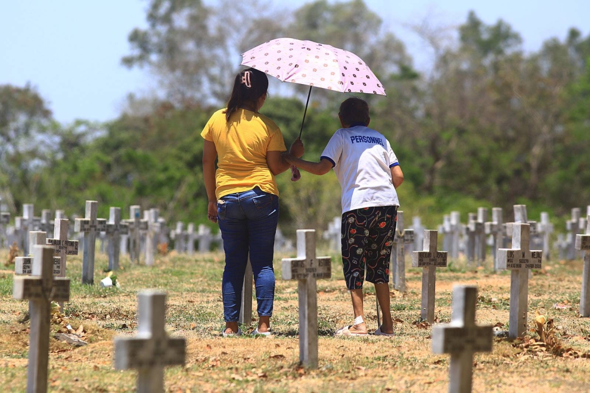 A soldier of the Philippine Army salutes the grave of a fallen soldier and families remember their dead during the Day of Valor or 'Araw ng Kagitingan' inside the Libingan ng mga Bayani (LNMB) in Taguig City, on Tuesday, April 9, 2024. PHOTOS BY MIKE ALQUINTO