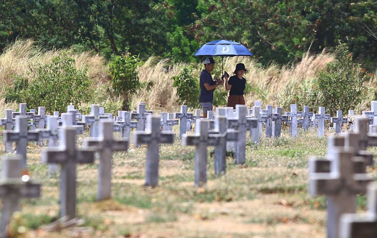 A soldier of the Philippine Army salutes the grave of a fallen soldier and families remember their dead during the Day of Valor or 'Araw ng Kagitingan' inside the Libingan ng mga Bayani (LNMB) in Taguig City, on Tuesday, April 9, 2024. PHOTOS BY MIKE ALQUINTO