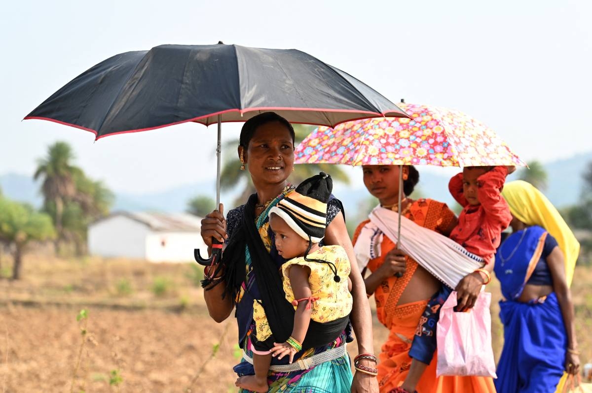 Tribal women shelter under the umbrellas from the sun during a local fair at Katekalyan in Dantewada district of India's Chhattisgarh state on April 16, 2024. AFP PHOTO