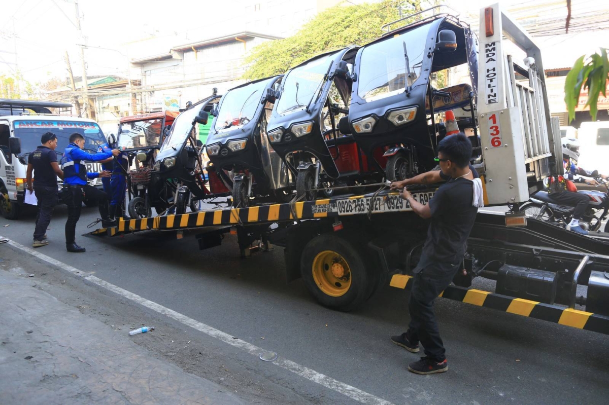 SEIZED Personnel of the Metropolitan Manila Development Authority strap e-trikes to a towing truck on Thursday, April 18, 2024. PHOTO BY MIKE ALQUINTO