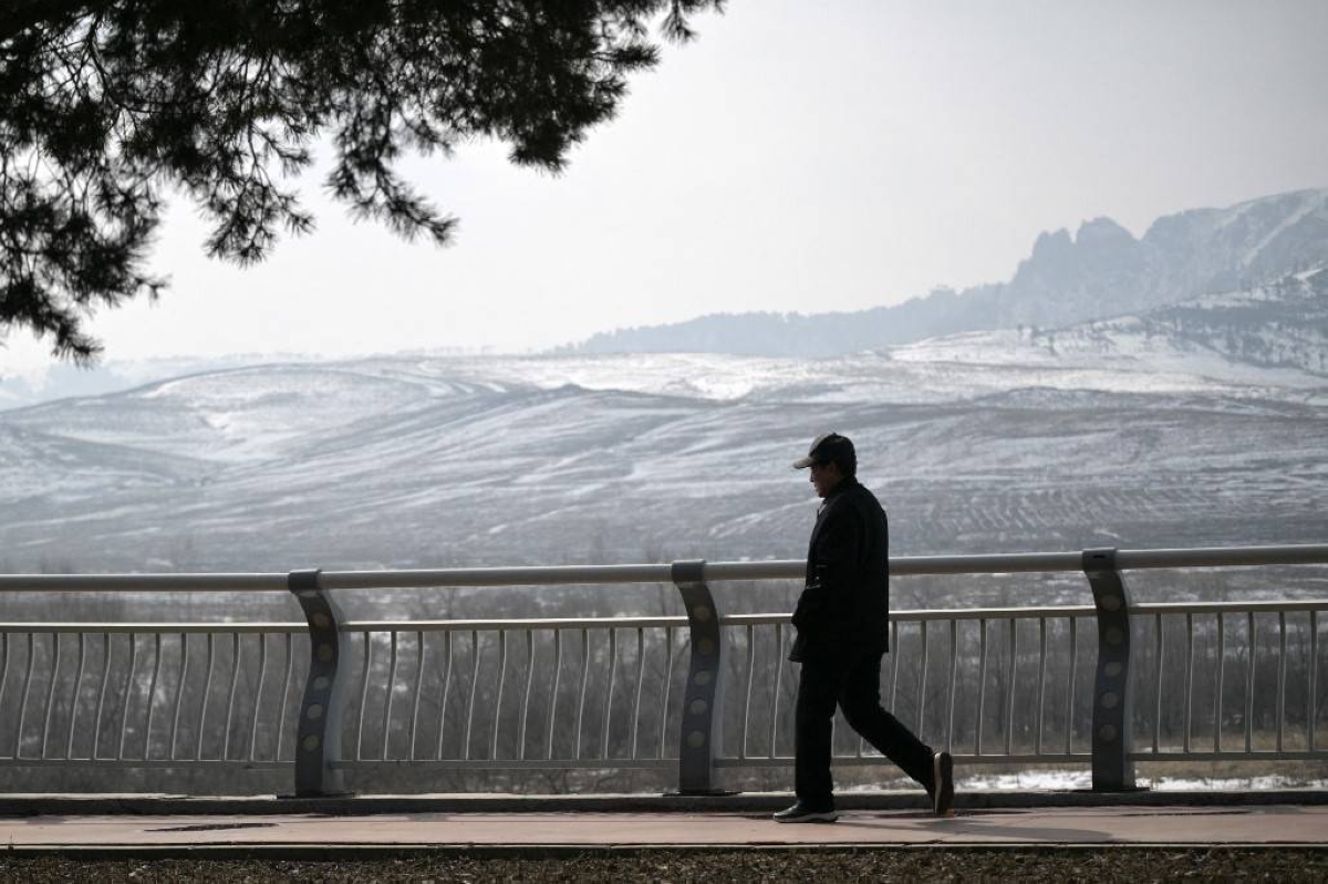 This photo taken on February 29, 2024 shows a man walking along the Yalu River in the city of Linjiang in the province of Jilin, northeast China, which is along the border with North Korea's county of Chunggang. AFP PHOTO