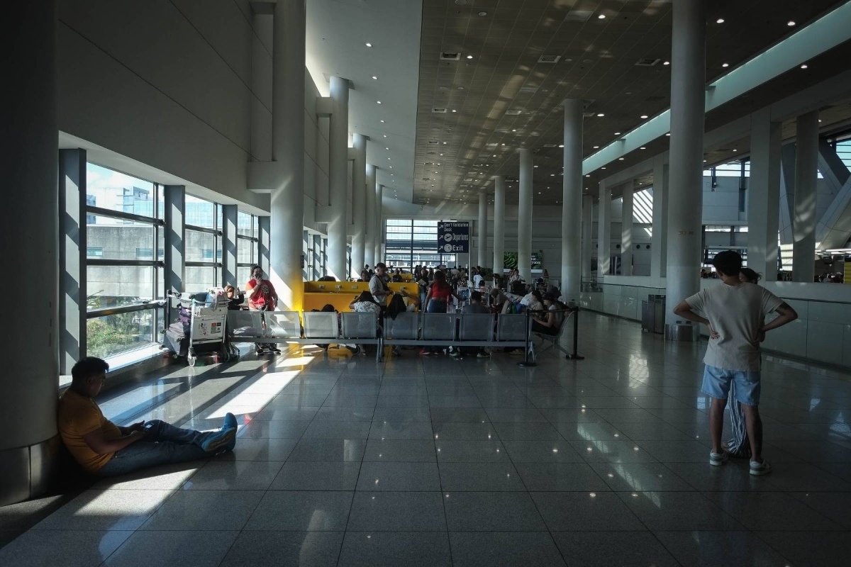尼诺·阿基诺国际机场 (NAIA) 3 号航站楼内的乘客在两座冷却塔进行维护时承受着高温。 摄影：J. GERARD SEGUIA
