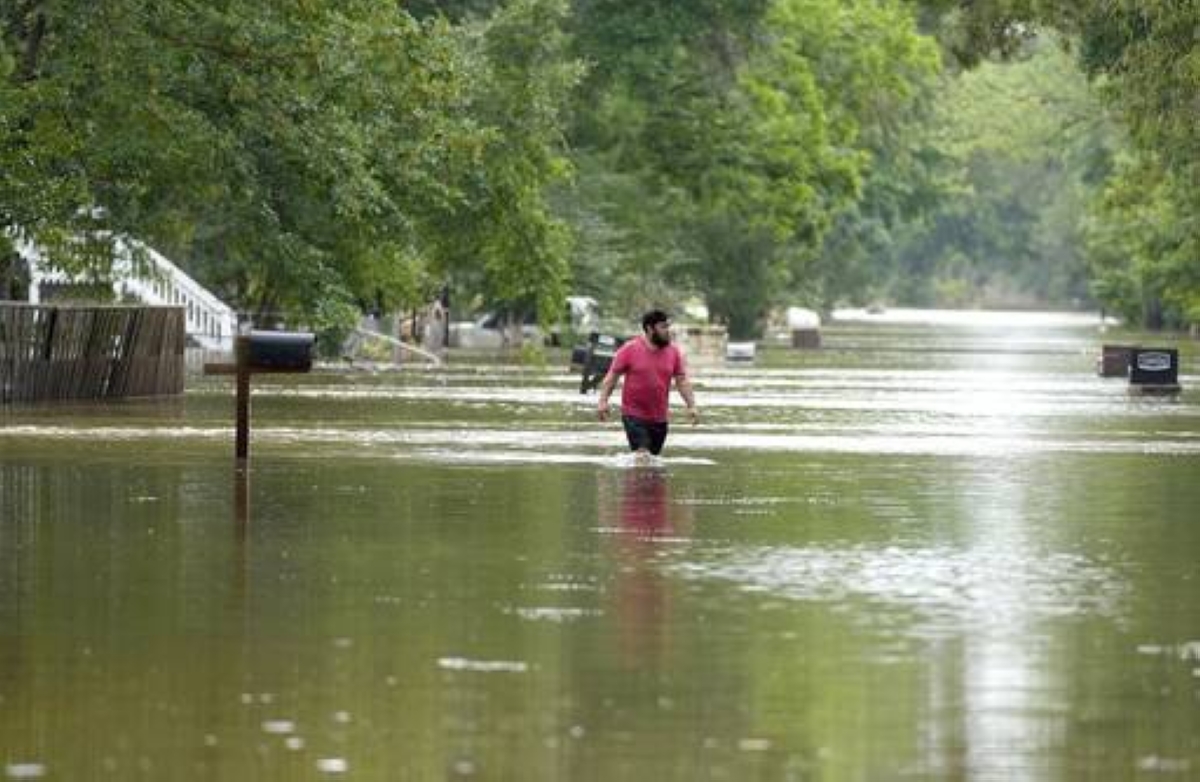 Woodloch, Texas: A man walks through floodwaters on River Oaks Drive, Saturday, May 4, 2024, in Woodloch, Texas. (Karen Warren/Houston Chronicle via AP)
