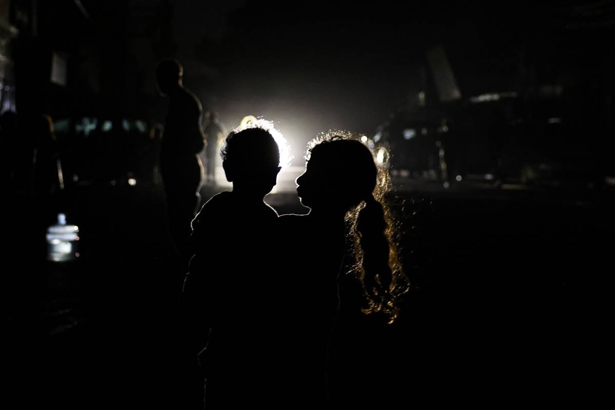 VICTIMS OF WAR A Palestinian woman holding a child is silhouetted against the lights of an incoming car in Rafah, in the southern Gaza Strip, on Saturday, May 4, 2024. AFP PHOTO