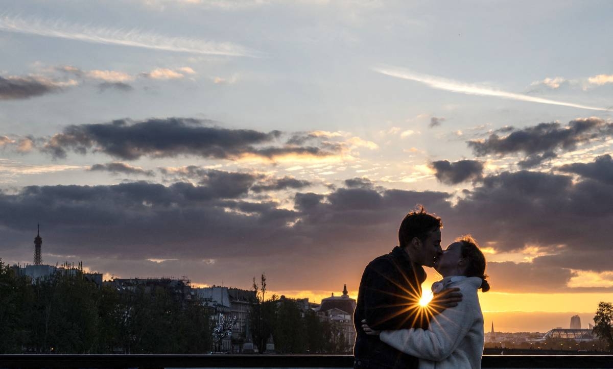 A couple kiss at sunset on the Pont des Arts bridge over the river Seine, in Paris on April 23, 2024. Photo by Martin BUREAU / AFP