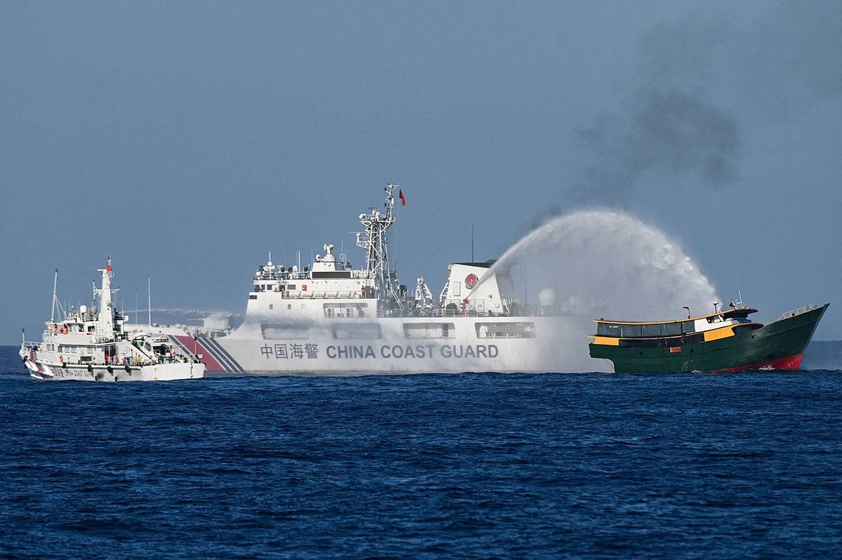 This photo taken on March 5, 2024 shows China Coast Guard vessels deploying water cannons at the Philippine military chartered Unaizah May 4 (R) during its supply mission to Second Thomas Shoal in disputed waters of the South China Sea. JAM STA ROSA / AFP