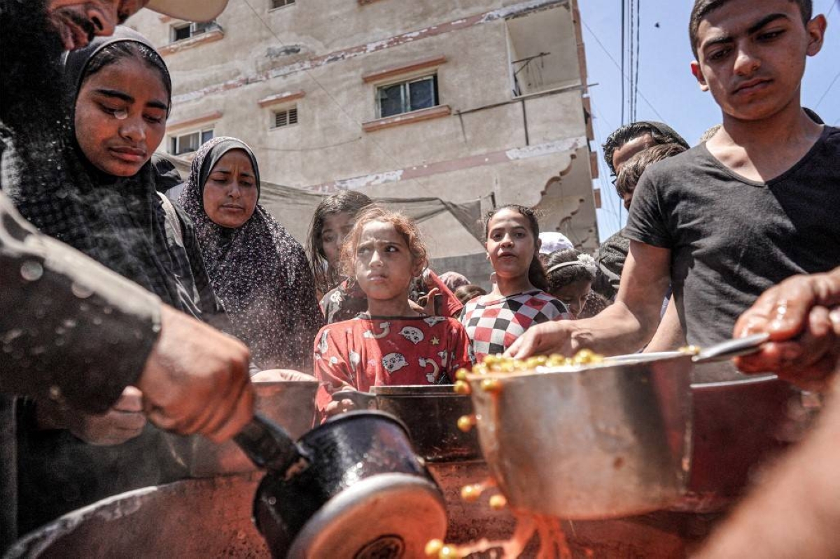 PASS THOSE POTS People are handed out food from a large pot at a public kitchen in the city of Deir el-Balah, central Gaza Strip, on May 13, 2024. AFP PHOTO