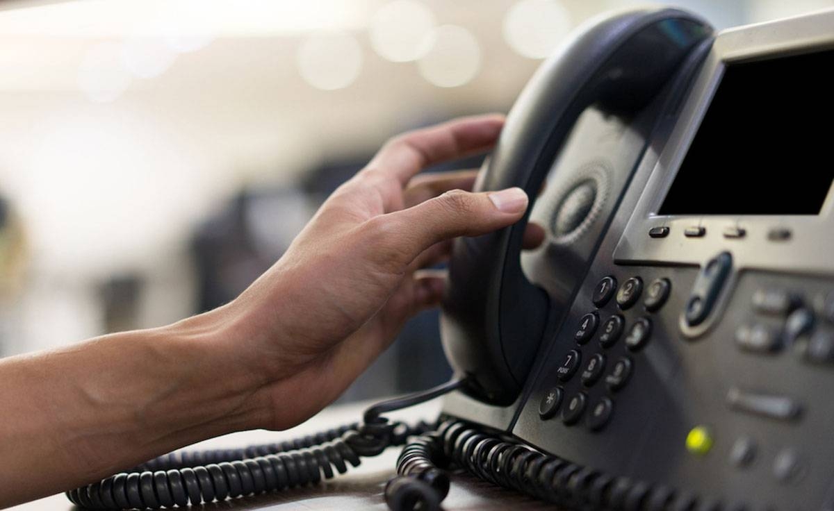Close-up of a male employee touching the handset of a telephone on the desk to contact customers or receive calls, hotline concept. CONTRIBUTED PHOTO