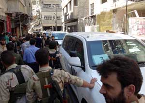 A handout image released by the Syrian opposition’s Shaam News Network shows rebel fighters and civilians surrounding the vehicles of the United Nations arms experts as they arrive to inspect a site suspected of being hit by a deadly chemical weapons attack last week on Wednesday in the Eastern Ghouta area on the northeastern outskirts of Damascus. AFP PHOTO