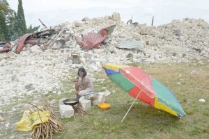 A woman on Wednesday cooks near the ruins of the 180-year-old Our Lady of Light Church in Bohol a day after a 7.2 magnitude quake hit Central Visayas. Rescue workers raced to reach isolated communities to save people who may be trapped under rubble. AFP PHOTO