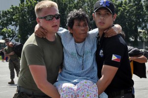 An American and Filipino soldier carry a sickly survivor from a C-130 plane that flew her and other victims from Tacloban to Manila. Photo By Edwin Muli