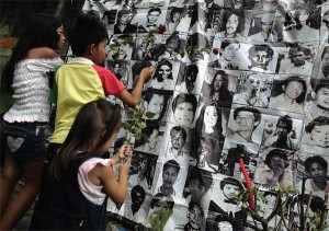 With no graves to visit, relatives of desaparecidos offer prayers and flowers Saturday in front of photos of missing persons and victims of extrajudicial killings at the compound of the Baclaran church. PHOTO BY RENE H. DILAN