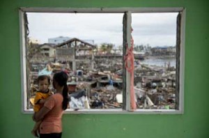 A typhoon victim looks at her devastated waterfront community from the window of a partial standing building in Tacloban City. Experts say it will cost billions of dollars and take years to revive communities that were flattened by Super Typhoon Yolanda. AFP PHOTO