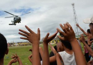 Residents wave to a US Navy Seahawk helicopter which dropped off relief goods in the town of Giporlos, Eastern Samar, on Saturday. Spearheaded by a US aircraft carrier group, foreign relief efforts have stepped up a gear eight days after Super Typhoon Yolanda left thousands dead and millions homeless.  AFP PHOTO/TED ALJIBE 