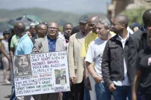 A man holds a portrait of Nelson Mandela as people queue to bid farewell to South African former president Nelson Mandela lying in state outside the Union Buildings on Thursday in Pretoria. AFP PHOTO