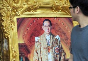 A Thai man walking past a photograph of King Bhumibol Adulyadej kept for sale at a side street on the eve of his birthday in Bangkok on Wednesday. AFP PHOTO