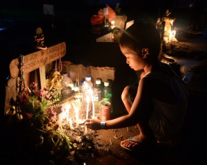  A girl lights a candle for a departed friend at a mass grave for victims of the disaster in front of a chapel in the village of San Joaquin in Palo, Leyte on Tuesday.  AFP PHOTO 