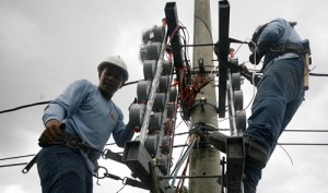 Meralco linemen install electric meters along Batasan Road in Quezon City. The power distributor announced a huge rate increase this month.  Photo By Miguel De Guzman 