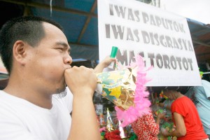 A man blows a paper horn (torotot) as he peddles noisemakers at the Commonwealth market in Quezon City on Sunday. At P10 to P20 each, colorful paper horns are safer than firecrackers, which can cause injuries. PHOTO BY MIGUEL DE GUZMAN