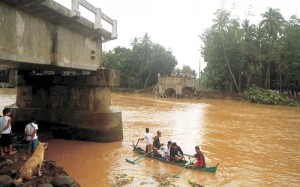  Residents ride a wooden boat as they cross a river after the bridge collapsed overnight due to flooding brought about by heavy rains in Linamon town, Lanao del Norte province. AFP PHOTO 