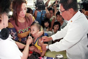 Health Secretary Enrique Ona vaccinates a child against measles at the Welfareville Compound in Mandaluyong City. PNA