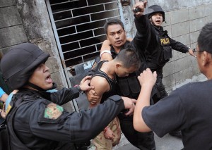 Police escort to safety one of the four hostages seized by Jerry Lo in La Loma, Quezon City, on Monday. The knife-wielding Lo held his mother and three cousins captive for 3 hours before he surrendered. PHOTO BY MIKE DE JUAN