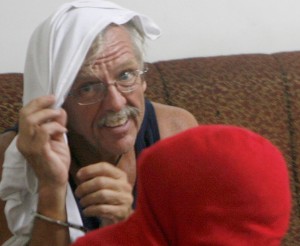 Retired US Navy Robert Mark Stasaitis (with head covered in white towel) is interviewed by police after robbing and holding hostage the cashier of the Paradise apartel in Timog, Quezon City, where he was staying. PHOTO BY MIGUEL DE GUZMAN