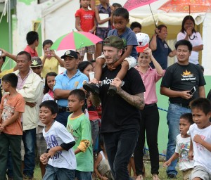 International football superstar David Beckham carries a boy on his shoulders following an impromptu football game with young survivors of Super Typhoon Yolanda in Tanauan town, Leyte on Friday. Besides being one of the top professional football players in the world, Beckam is also a Unicef ambassador. AFP PHOTO