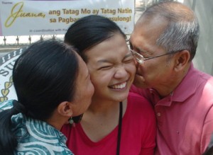 Jana Monica Valenzuela, one of the examinees who passed the 2013 Bar exams, beams as she is kissed by her parents. PHOTO BY  EDWIN MULI 