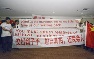 Chinese relatives of passengers from missing Malaysia Airlines flight MH370 display banners and the Chinese flag at a hotel in Subang Jaya on March 30, 2014. Thirty-nine Chinese relatives of passengers on board missing flight MH370 arrived in Malaysia earlier in the day to press for answers about the fate of their loved ones. AFP PHOTO