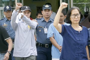 Benito and Wilma Tiamzon raise their fists as they walk out of the Criminal Investigation and Detection Group office in Camp Crame where they were taken after their arrest in Cebu. PHOTO BY MIGUEL DE GUZMAN